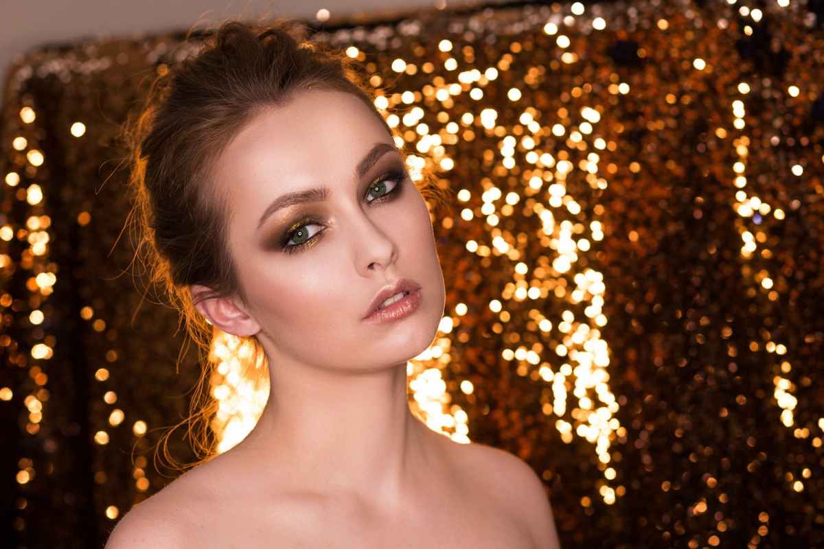 donna truccata con dietro uno sfondo di brillantini