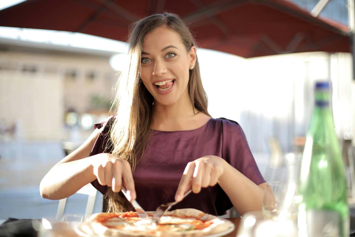 ragazza che mangia una pizza e sorride