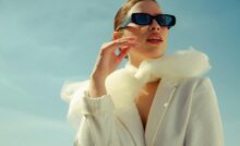 donna con una giacca bianca un foulard bianco e degli occhiali da sole