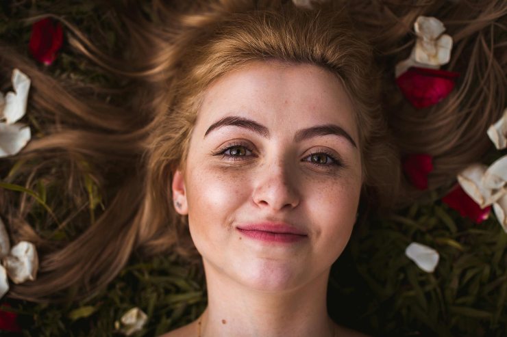 ragazza sdraiata con i capelli ricoperti da petali di rose