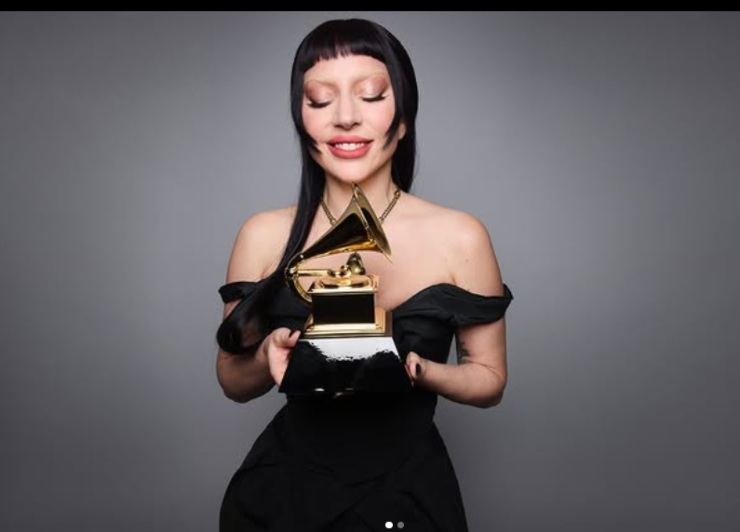 lady gaga che sorride con in mano il Grammy a forma di tromba